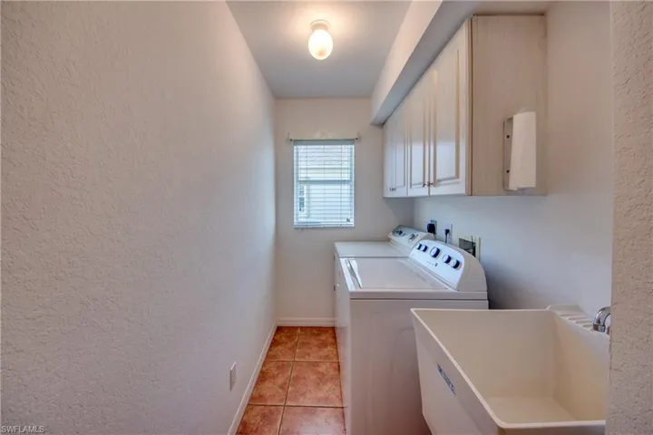 Washroom featuring cabinets, sink, light tile patterned floors, and independent washer and dryer