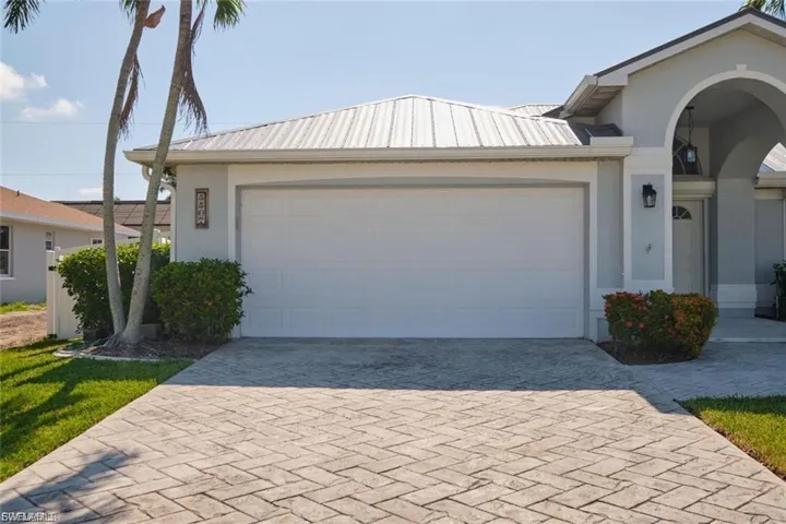Ranch-style home featuring stucco siding, decorative driveway, a metal roof, and an attached garage