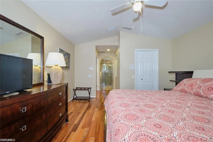 Bedroom featuring wood finished floors, a closet, arched walkways, ceiling fan, and lofted ceiling