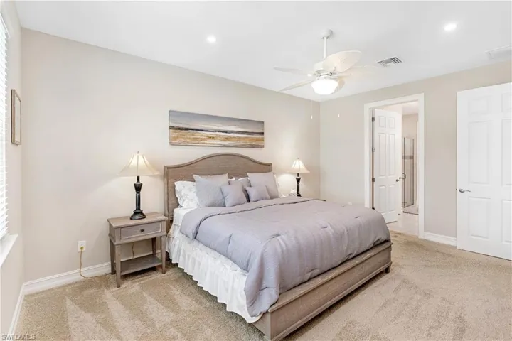 Bedroom featuring light carpet, recessed lighting, ceiling fan, and ensuite bath