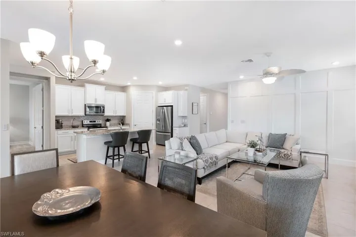 Living room with a chandelier, a decorative wall, recessed lighting, ceiling fan, and light tile patterned floors