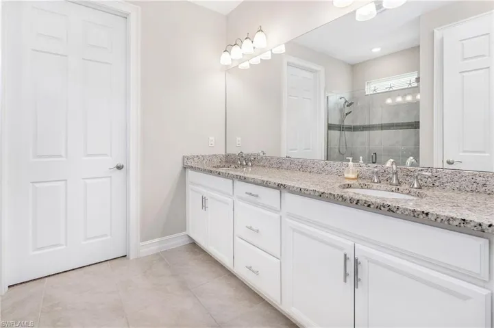 Bathroom with double vanity, a stall shower, and light tile patterned floors