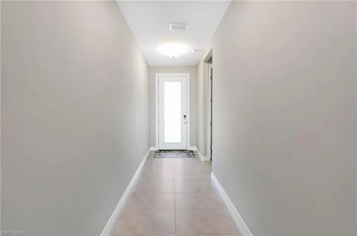 Doorway to outside featuring tile patterned floors and baseboards