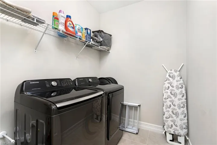Laundry area featuring light tile patterned floors and washing machine and dryer