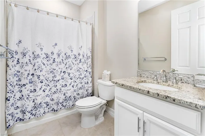 Bathroom with vanity, light tile patterned flooring, and shower / bath combo with shower curtain