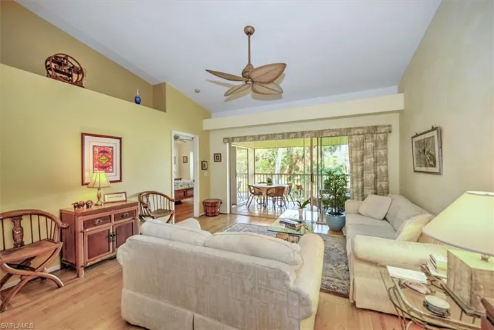 Living room with vaulted ceiling, ceiling fan, and light bamboo  flooring