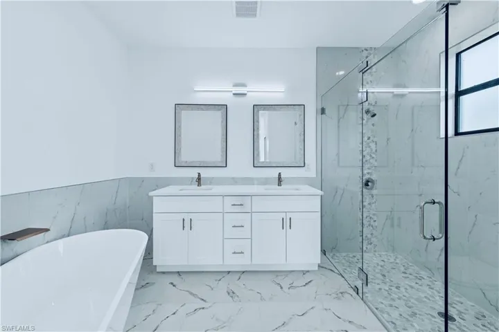 Bathroom with vanity, tile walls, and shower with separate bathtub