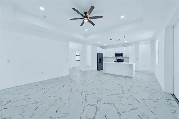 Unfurnished living room with a raised ceiling and ceiling fan