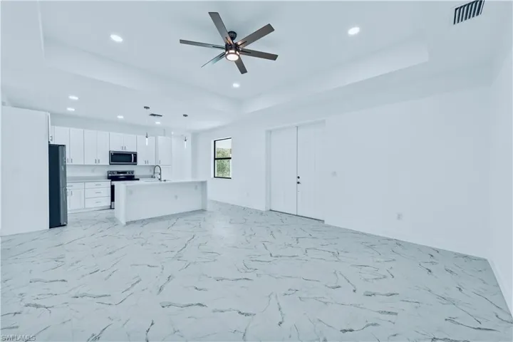 Kitchen featuring a kitchen island with sink, white cabinets, sink, appliances with stainless steel finishes, and decorative light fixtures