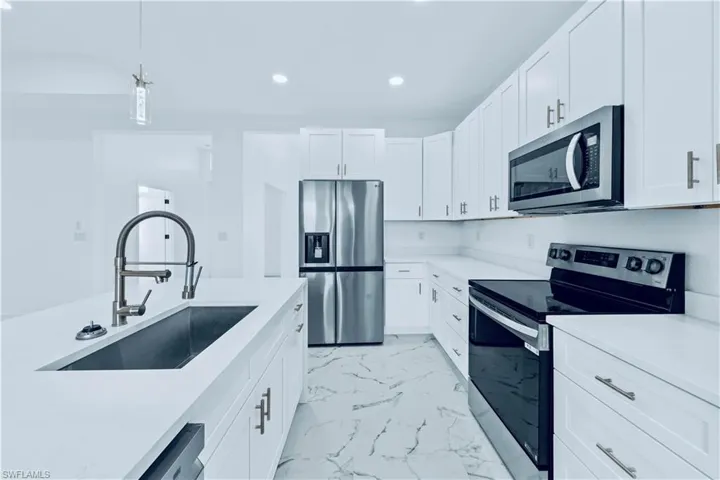 Kitchen featuring white cabinets, pendant lighting, stainless steel appliances, and sink