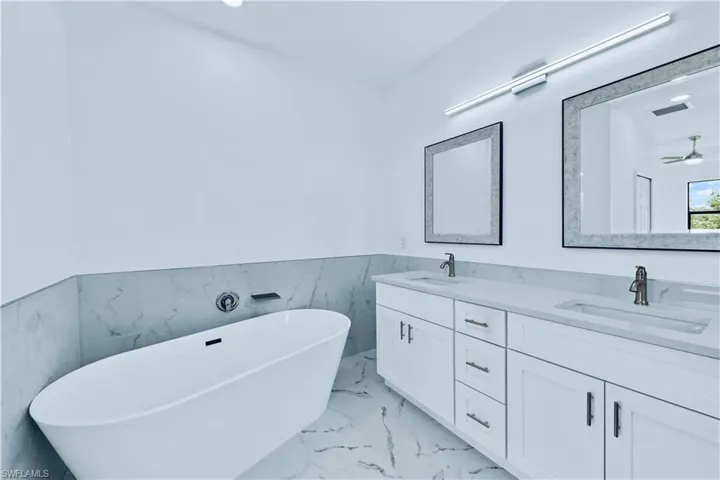 Bathroom with a washtub, vanity, tile walls, and ceiling fan