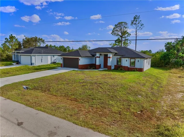 Ranch-style home featuring a garage and a front lawn
