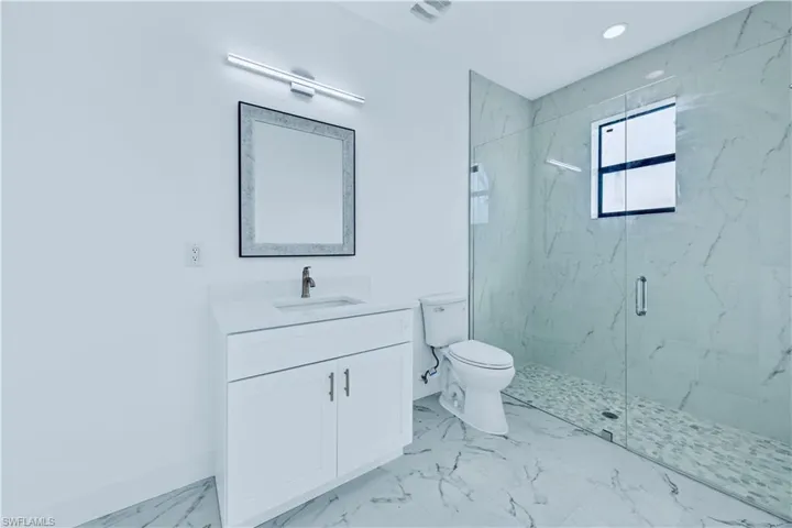 Bathroom featuring vanity, a shower with shower door, and toilet