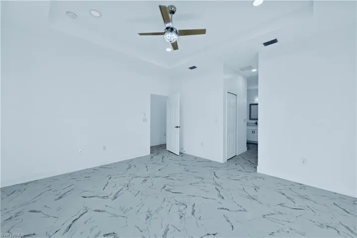 Empty room with ceiling fan and a raised ceiling