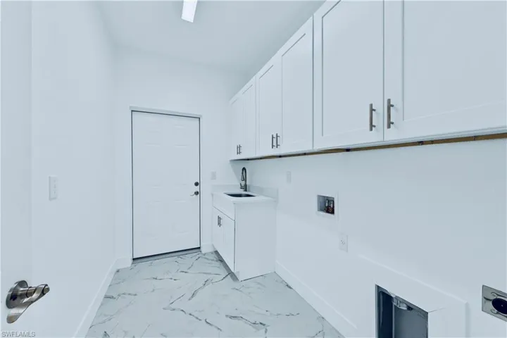 Washroom with cabinets, hookup for a washing machine, electric dryer hookup, and sink
