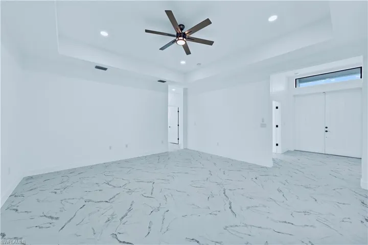 Empty room featuring ceiling fan and a tray ceiling