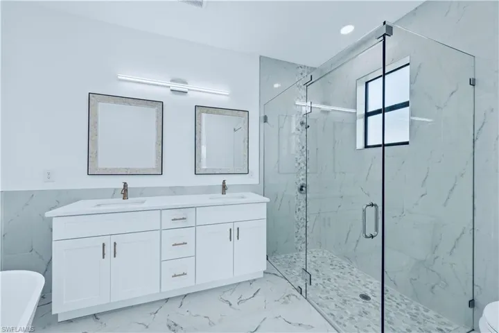 Bathroom with vanity, walk in shower, and tile walls