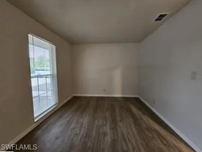 Unfurnished room featuring baseboards and dark wood-style flooring