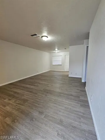 Empty room with dark wood finished floors, a textured ceiling, and a textured wall