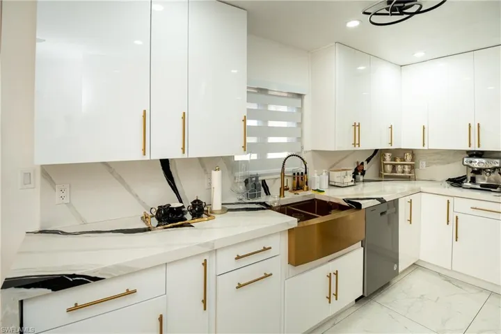 Kitchen featuring white cabinetry, light marble finish flooring, dishwasher, light stone countertops, and recessed lighting