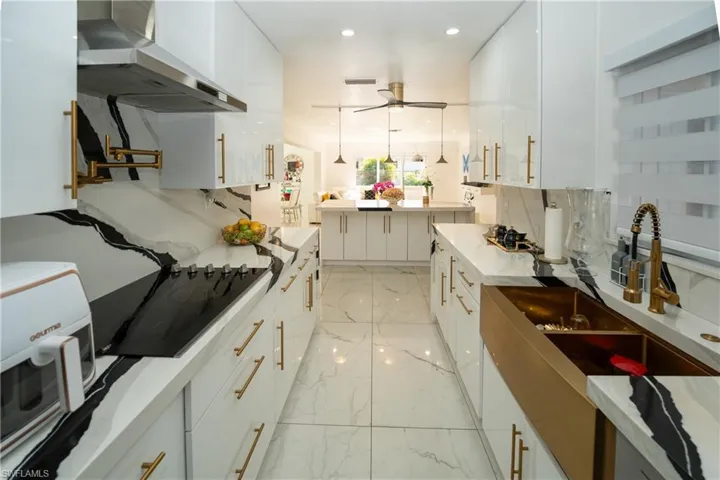 Kitchen with hanging light fixtures, white cabinetry, and black electric stovetop