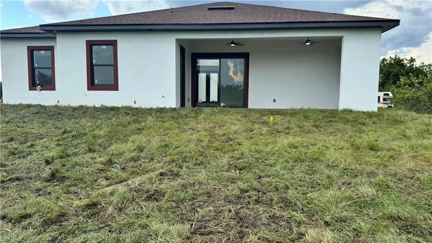 Rear view of property with a lawn and ceiling fan