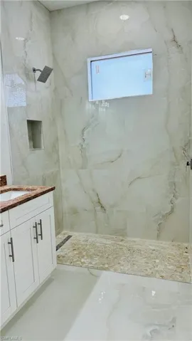 Bathroom with vanity and tiled shower
