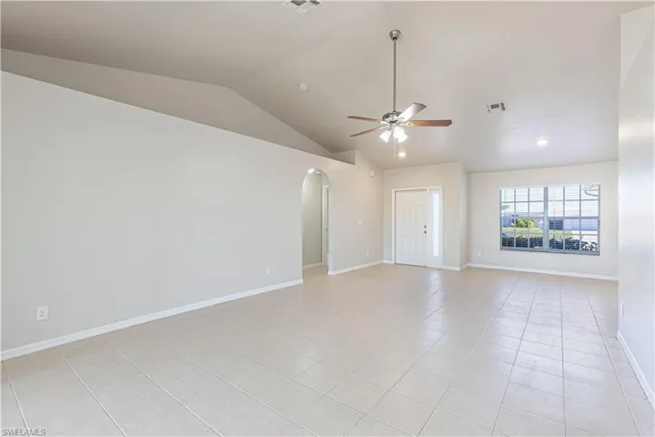 Spare room featuring arched walkways, a ceiling fan, and light tile patterned flooring