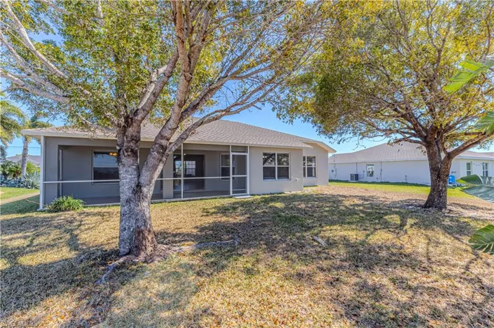 Back of property featuring stucco siding, a sunroom, and a yard