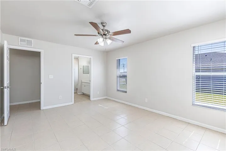 Unfurnished bedroom featuring ceiling fan, connected bathroom, and light tile patterned floors