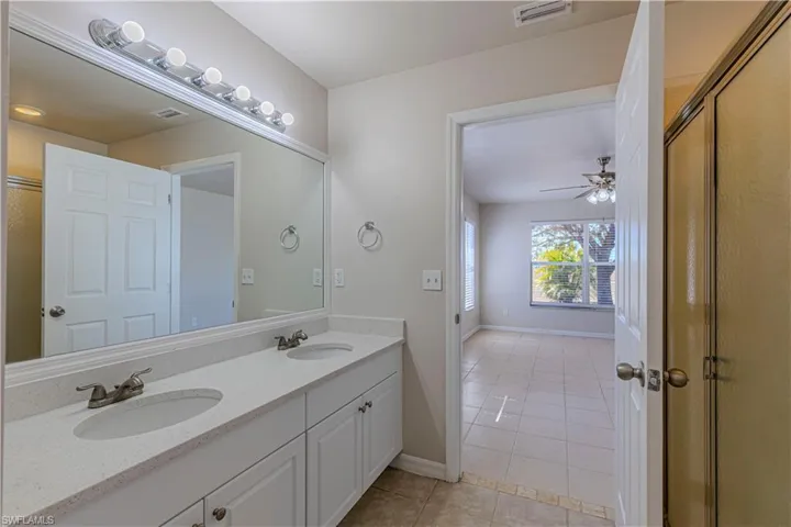 Full bathroom with light tile patterned flooring, double vanity, and a ceiling fan