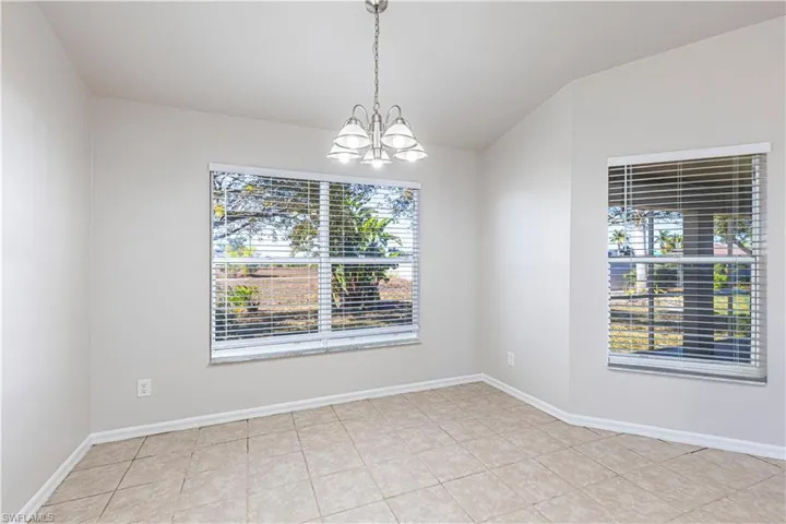 Unfurnished room with hanging lights, healthy amount of natural light, light tile patterned floors, and lofted ceiling