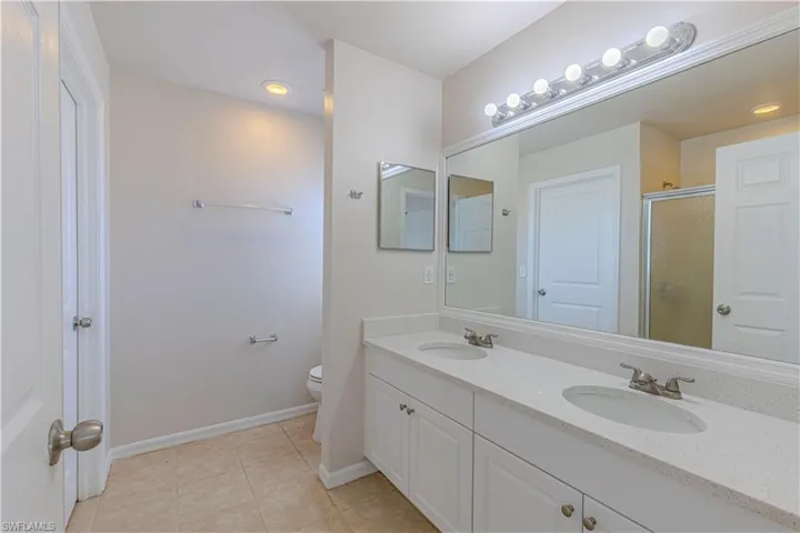 Full bath with double vanity, light tile patterned flooring, a shower stall, and recessed lighting