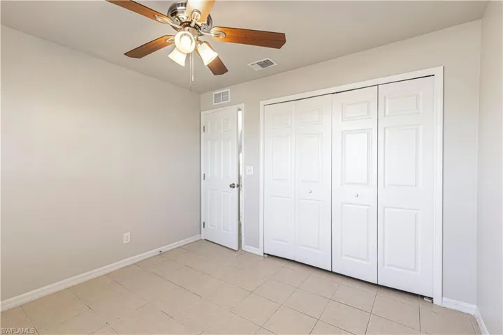 Unfurnished bedroom with ceiling fan, light tile patterned floors, and a closet