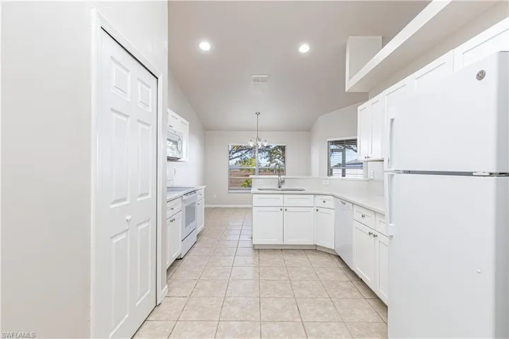 Kitchen with white appliances, lofted ceiling, a chandelier, light countertops, and a peninsula
