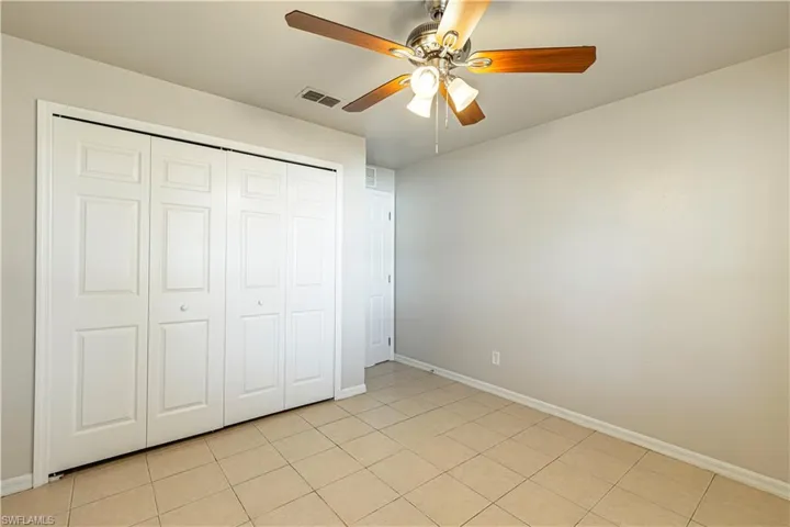 Unfurnished bedroom featuring a closet, ceiling fan, and light tile patterned floors
