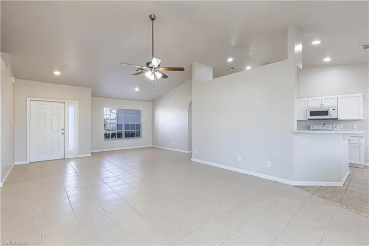 Unfurnished living room featuring a ceiling fan, light tile patterned flooring, vaulted ceiling, and recessed lighting