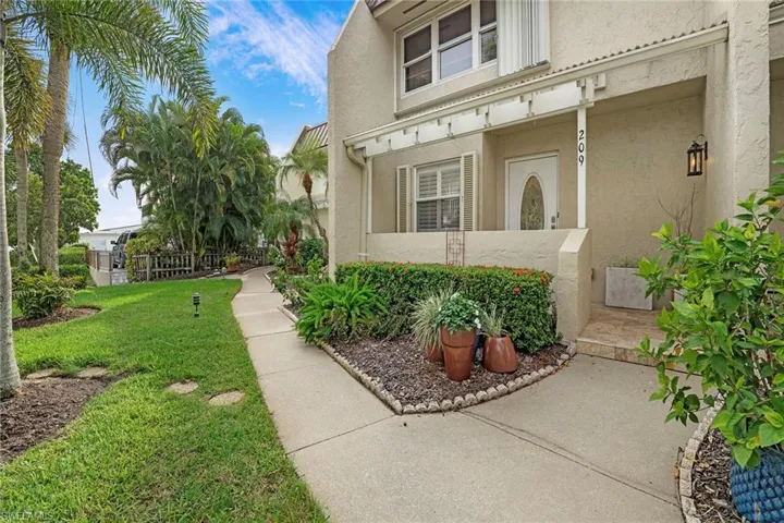View of exterior entry with stucco siding and a lawn