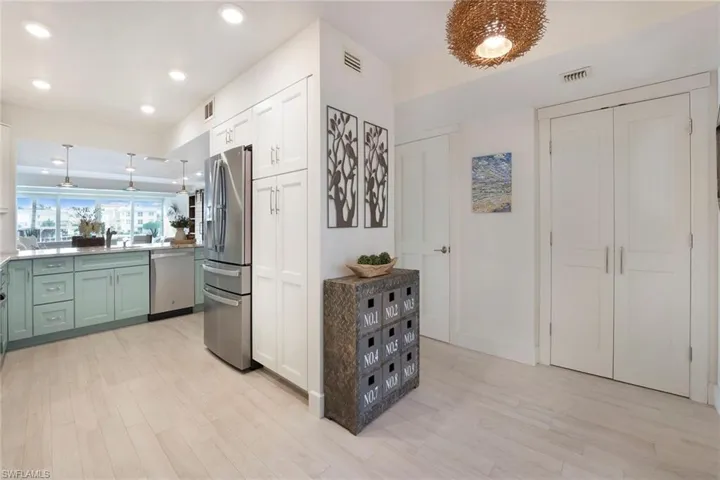 Kitchen with decorative light fixtures, appliances with stainless steel finishes, light wood-type flooring, recessed lighting, and white cabinetry