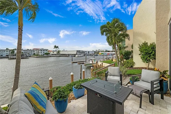 View of patio featuring a water view, a fire pit, and a dock