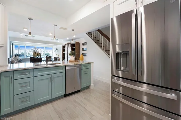 Kitchen with stainless steel appliances, light stone counters, decorative light fixtures, recessed lighting, and light wood-style floors