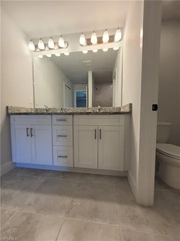 Bathroom with tile patterned flooring, double vanity, and toilet