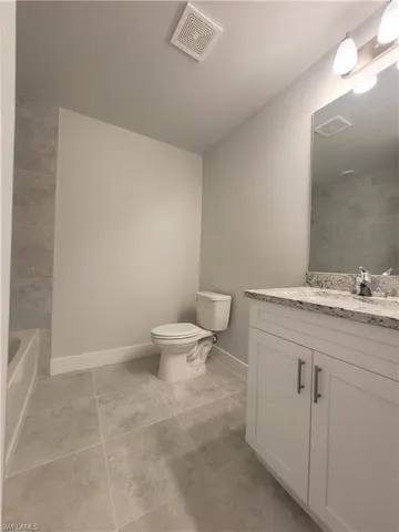 Full bathroom with tile patterned flooring, bathing tub / shower combination, toilet, and vanity