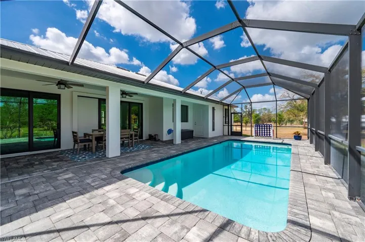 Swimming pool featuring outdoor dining area, a sunroom, a patio area, and a lanai