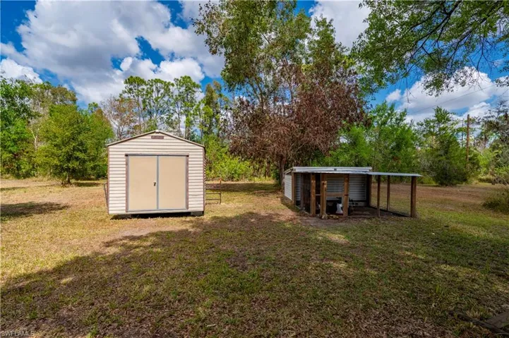 View of green lawn with exterior structure and a storage unit