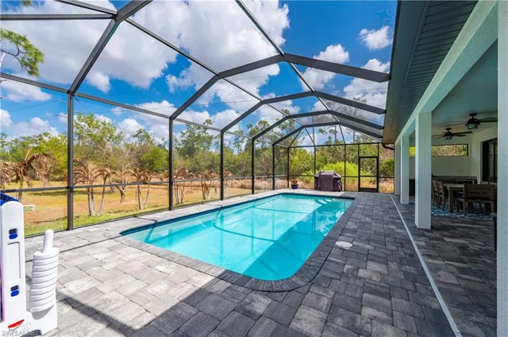 Outdoor pool featuring a sunroom, a patio area, glass enclosure, and a yard
