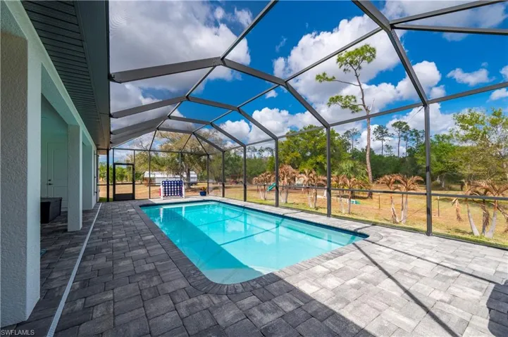Swimming pool with a sunroom, a lanai, and a patio area