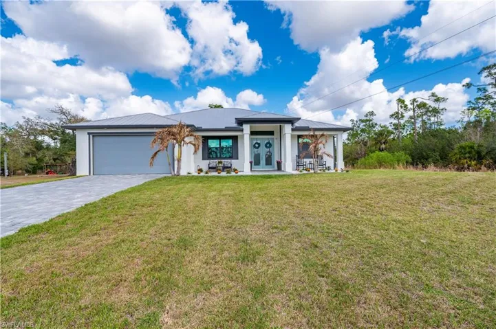 Ranch-style house with a front lawn, a garage, decorative driveway, and a metal roof