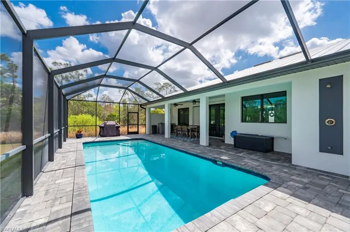 Outdoor pool featuring a sunroom, a patio, and glass enclosure