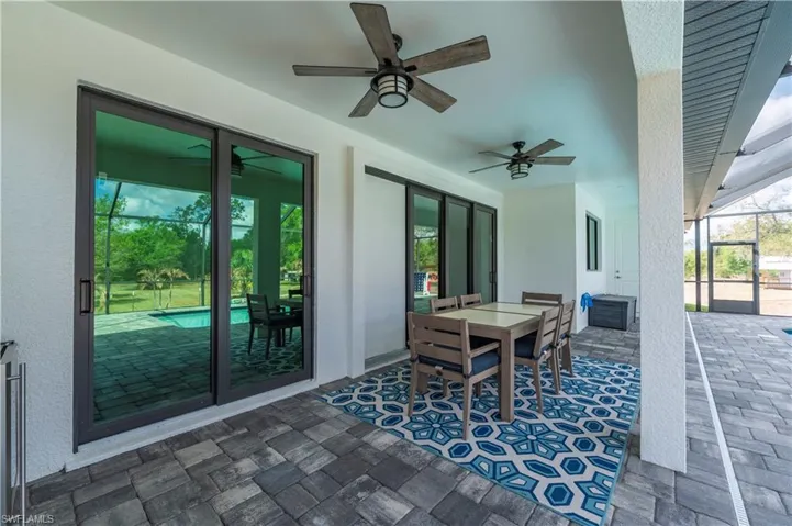 View of patio with outdoor dining space, a lanai, ceiling fan, and a sunroom